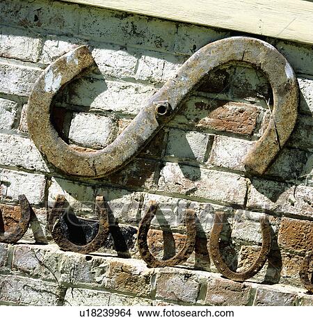 Picture - Row of old horseshoes on brick wall with metal reinforcing brace. Fotosearch