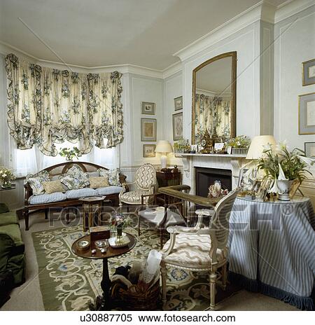 Stock Photography - Ruched floral blind and patterned rug in traditional living room. Fotosearch