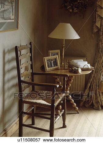 Stock Photo - Rush-seated ladderback chair and pine table with spindle legs in corner of country dining room. Fotosearch