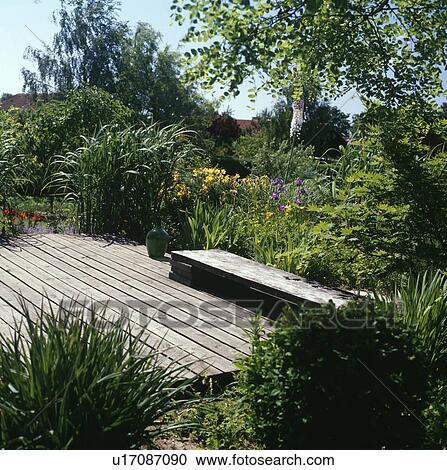 Rustic bench on wooden decking in large country garden in summer View Large Photo Image Stock Image - Rustic bench on wooden decking in large country garden in summer. Fotosearch