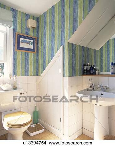Scales beside toilet in small attic bathroom with pedestal basin and green+blue striped wallpaper View Large Photo Image Picture - Scales beside toilet in small attic bathroom with pedestal basin and green+blue striped wallpaper. Fotosearch