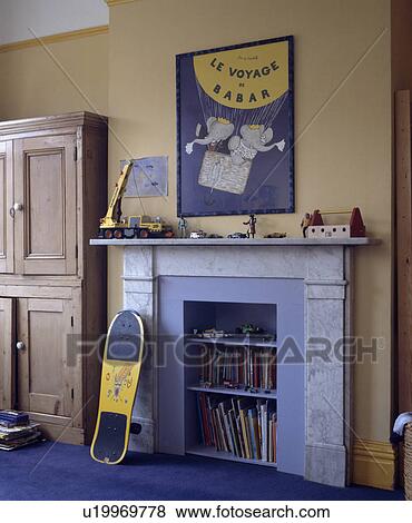 Stock Photo - Scateboard leaning against marble fireplace with books on integral blue shelves in child's bedroom with Babar poster. Fotosearch