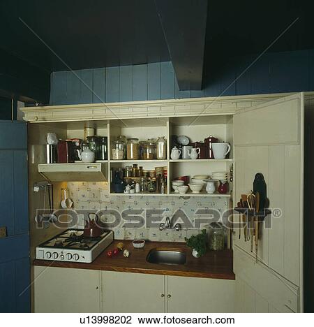 Small compact kitchen with portable hob and small sink below shelves with crockery in cupboard View Large Photo Image Stock Image - Small compact kitchen with portable hob and small sink below shelves with crockery in cupboard. Fotosearch