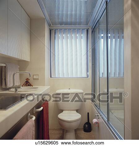 Stock Photography - Small modern white shower room with vertical blinds and wc.. Fotosearch