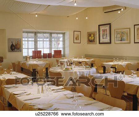 Stock Photograph - Small restaurant diningroom with white cloths on tables and tented ceiling. Fotosearch