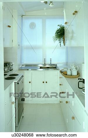 Stock Photo - Small white spacesaving kitchen with white blind and white flooring. Fotosearch