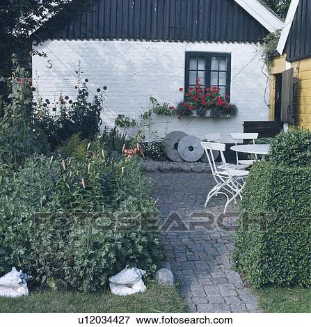 Stone paving on path and patio in front of small white cottage View Large Photo Image Stock Photo - Stone paving on path and patio in front of small white cottage. Fotosearch