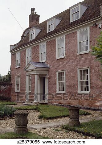 Stock Photography - Stone urns in knot garden in front of detached Queen Anne country house. Fotosearch