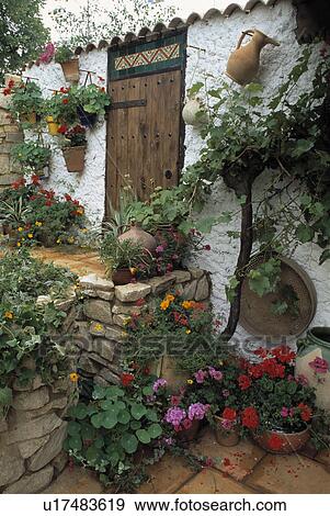 Stock Photo - Summer flowering plants in front of white Mediterranean cottage with low stone wall. Fotosearch