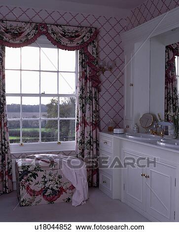 Swagged floral curtains and matching upholstered ottoman below window in traditional country bathroom View Large Photo Image Stock Image - Swagged floral curtains and matching upholstered ottoman below window in traditional country bathroom. Fotosearch