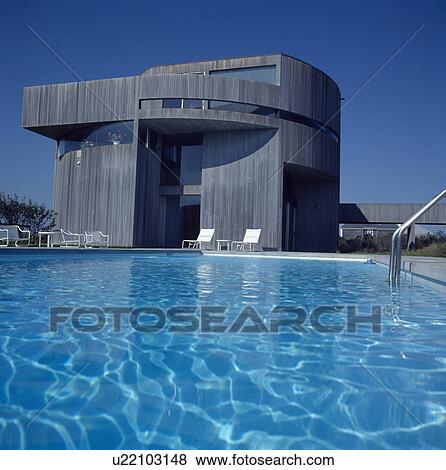 Swimming pool in front of large modern wooden-clad house on the coast View Large Photo Image Stock Photo - Swimming pool in front of large modern wooden-clad house on the coast. Fotosearch