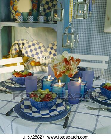 Stock Photo - table with blue glass and blue and white checked crockery on table with candles in lanterns and blue holders . Fotosearch