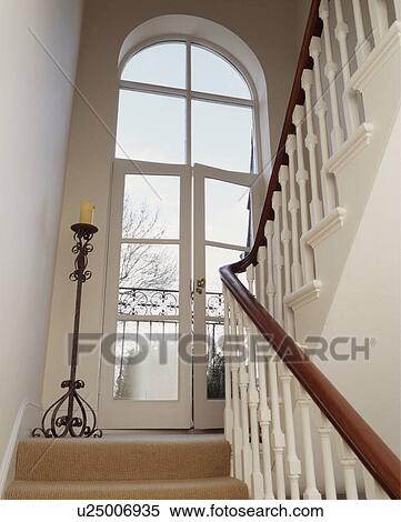 Tall iron candlestick beside open French windows on white staircase View Large Photo Image Stock Photography - Tall iron candlestick beside open French windows on white staircase. Fotosearch