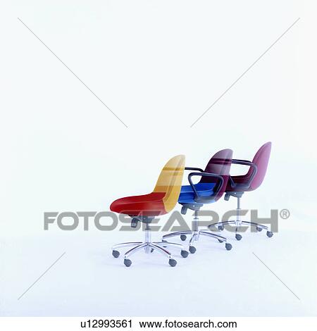 Stock Image - Three office chairs of various colours on casters. &#13; &#10; &#13; &#10; &#13; &#10;. Fotosearch