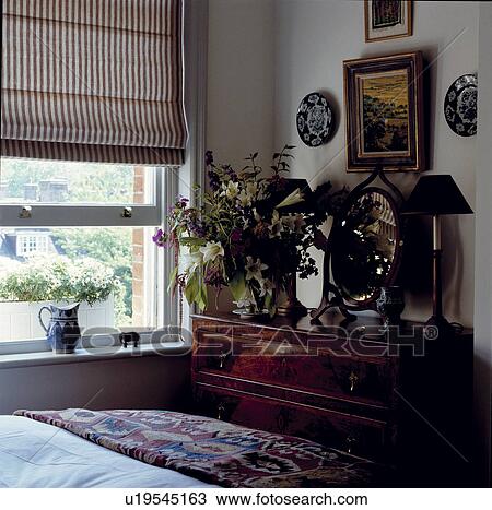 Traditional white bedroom with an antique chest of drawers and a Roman blind View Large Photo Image Stock Image - Traditional white bedroom with an antique chest of drawers and a Roman blind. Fotosearch