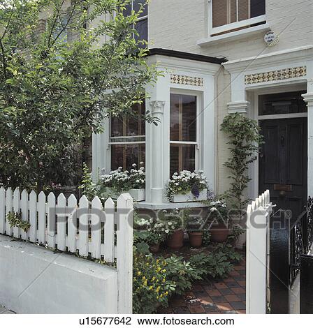 Stock Image - Traditional white Victorian town house with bay window and white fence. Fotosearch