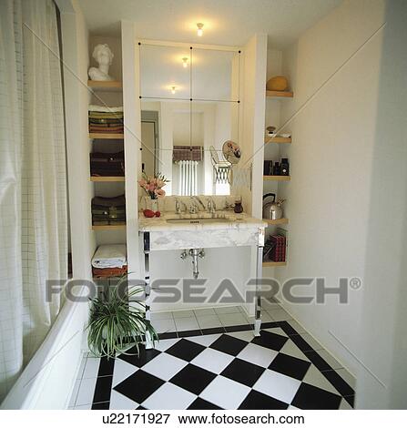 Stock Photo - Underset basin in marble unit below mirrored wall tiles in bathroom black+white chequerboard ceramic floor tiles. Fotosearch