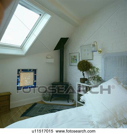 Stock Photography - Velux window above small stained glass window in modern attic bedroom with small black stove. Fotosearch
