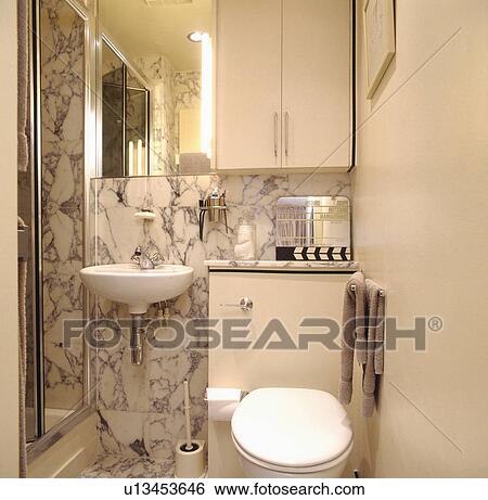 Wall mounted white basin and marble tiles in small modern white shower room View Large Photo Image Stock Photograph - Wall mounted white basin and marble tiles in small modern white shower room. Fotosearch