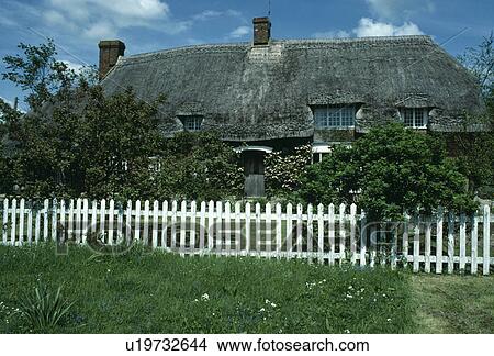 White picket fence in front of country cottage with thatched roof View Large Photo Image Picture - White picket fence in front of country cottage with thatched roof. Fotosearch