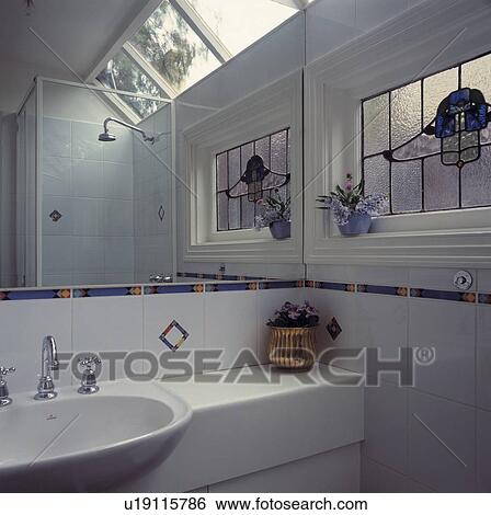 Stock Photograph - White tiled architectural bathroom with stained glass window and coloured tile detail.. Fotosearch
