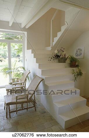 Wicker loungers below white stone modern stairs without bannisters in modern country hall View Large Photo Image Stock Photograph - Wicker loungers below white stone modern stairs without bannisters in modern country hall. Fotosearch