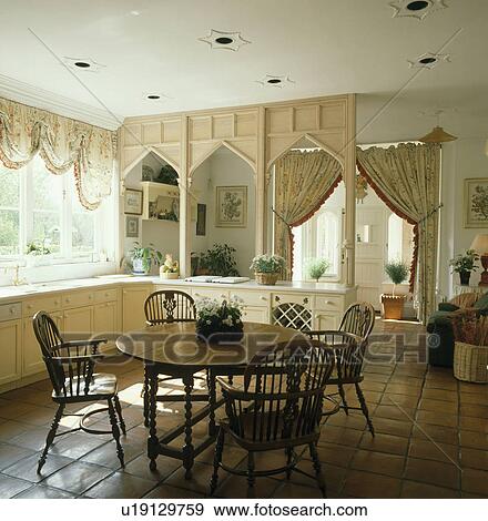 Windsor chairs and gateleg table in neutral kitchen with wooden room divider and terracotta tiled floor View Large Photo Image Stock Photo - Windsor chairs and gateleg table in neutral kitchen with wooden room divider and terracotta tiled floor. Fotosearch