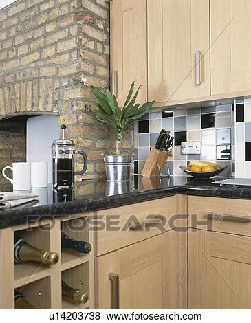 Wine stored in cube shelves below granite worktop with cafetiere and cups in modern pale wood kitchen View Large Photo Image Stock Photo - Wine stored in cube shelves below granite worktop with cafetiere and cups in modern pale wood kitchen. Fotosearch