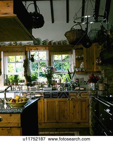 Wire and wicker baskets on hanging plate rack in small country kitchen with wooden units and black Aga View Large Photo Image Stock Photo - Wire and wicker baskets on hanging plate rack in small country kitchen with wooden units and black Aga. Fotosearch