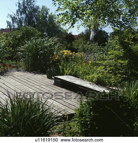 Wooden bench on decking in country garden View Large Photo Image Stock Image - Wooden bench on decking in country garden. Fotosearch