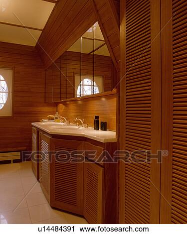 Wooden louvre doors on fitted cupboard in modern panelled bathroom with mirrored cabinets above basins View Large Photo Image Stock Image - Wooden louvre doors on fitted cupboard in modern panelled bathroom with mirrored cabinets above basins. Fotosearch