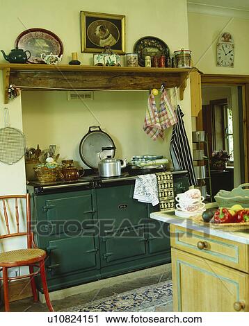 Stock Image - Wooden shelf above green Aga in traditional country kitchen. Fotosearch