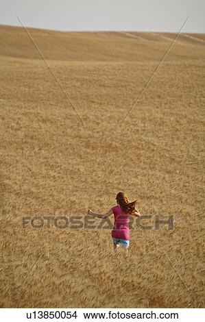 Picture -  girl children redhead running through wheat crop . Fotosearch