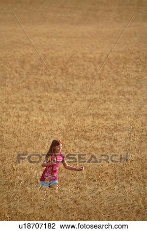 Stock Image -  girl redhead walking in wheat field . Fotosearch