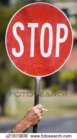 Stock Photograph -  hand person red white stop sign held holding lit cigarette. Fotosearch