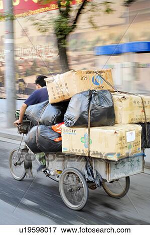 Stock Photo -  man male pedaling tricycle filled stacked boxes . Fotosearch