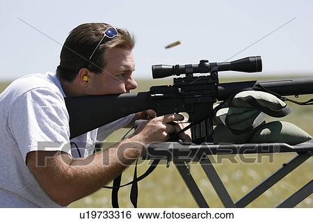 Stock Photograph -  man male shooting rifle ejected cartridge case . Fotosearch