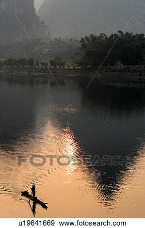 Stock Photo -  man sun male paddles bamboo raft lijiang river . Fotosearch