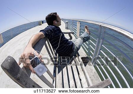music summer man male sitting bench pier ipod View Large Photo Image Stock Photo - music summer man male sitting bench pier ipod . Fotosearch