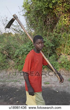 Stock Photograph -  people person tanzania boy carrying hoe walks. Fotosearch