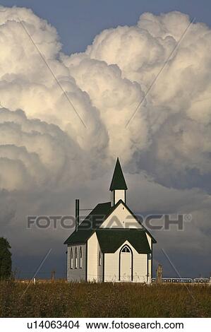 Picture -  summer clouds forming behind country church . Fotosearch