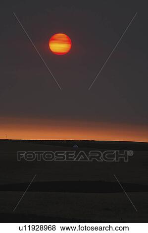 Stock Photo -  sun art rising behind thin clouds in scenic sun . Fotosearch