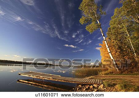 Stock Image -  water art boat dock autumn trees lake wispy body. Fotosearch