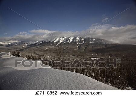 Stock Image -  winter rocky mountains in snow covered clouds. Fotosearch