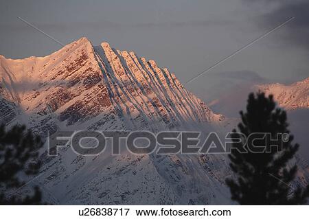 Stock Photo -  winter rocky mountains in snow covered shadows. Fotosearch