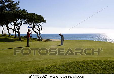 Stock Image -  woman golf man golfing expensive ocean club . Fotosearch