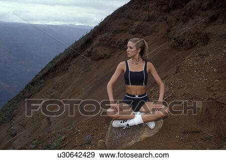 Stock Photo -  woman model sitting canyon rim in running outfit. Fotosearch