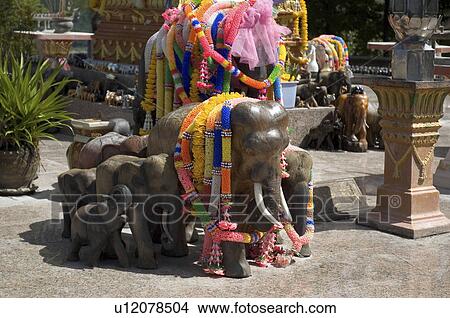 Picture -  wooden elephant statues given offerings in thai. Fotosearch