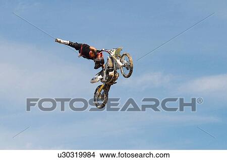 Picture -  background motocross rider performing stunt air. Fotosearch