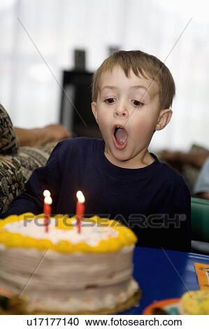 Stock Image -  child birthday young boy blows out candles cake. Fotosearch